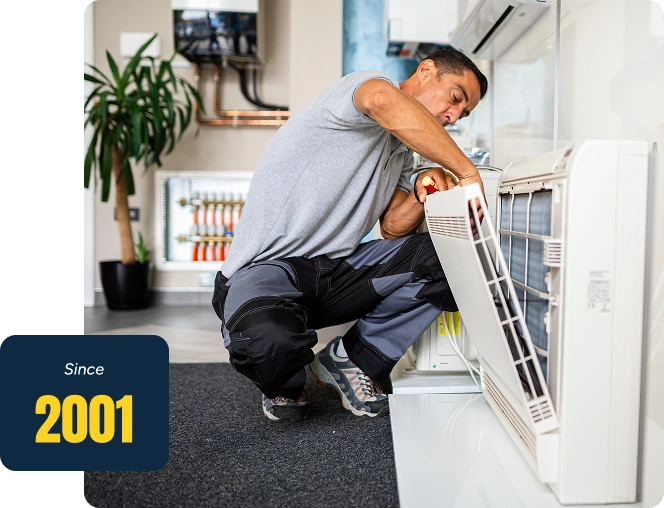 Man in a squat position on the floor, holding an object in his hand, repairing an air conditioner