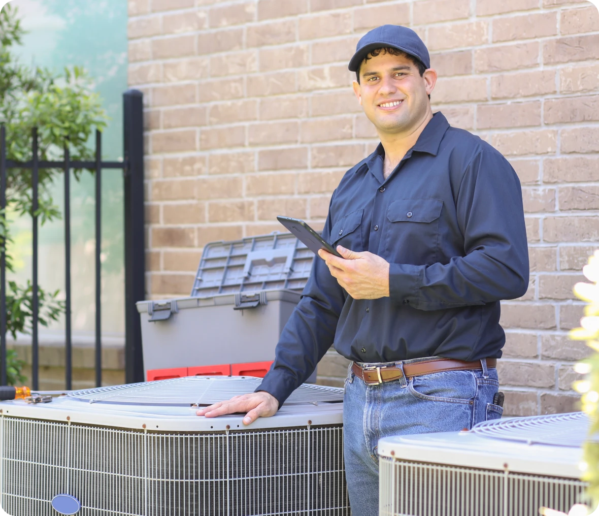 Man standing in front of an air conditioner, holding a tablet in his hand